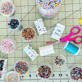 Small beaded felt birthday cakes in progress by Heather Donohue Crafts. Shows beads and sewing tools.